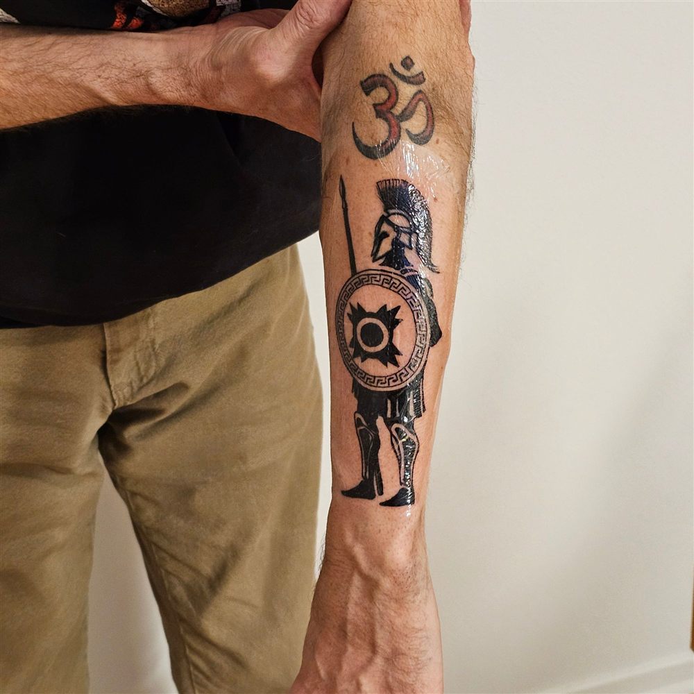 Blackwork Spartan warrior with shield and spear tattooed on a forearm by Jungle Earth Tattoos