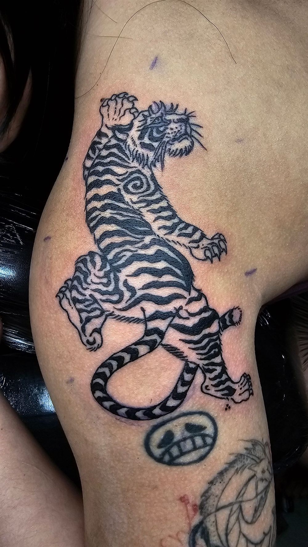 Black and white climbing tiger tattoo on a thigh by Jungle Earth Tattoos